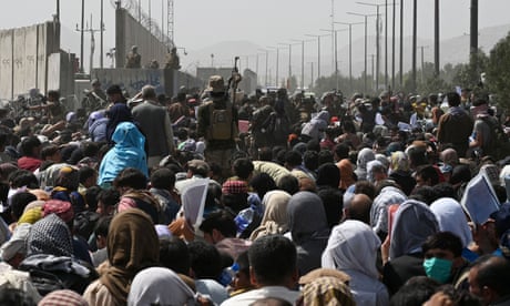 Afghans gather on a roadside at Kabul airport after the Taliban's military takeover in August 2021