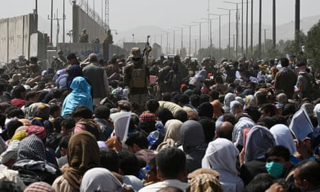 Afghans gather on a roadside at Kabul airport after the Taliban's military takeover in August 2021