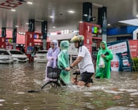 People wade through flood waters near a petrol station in Bangkok on Saturday