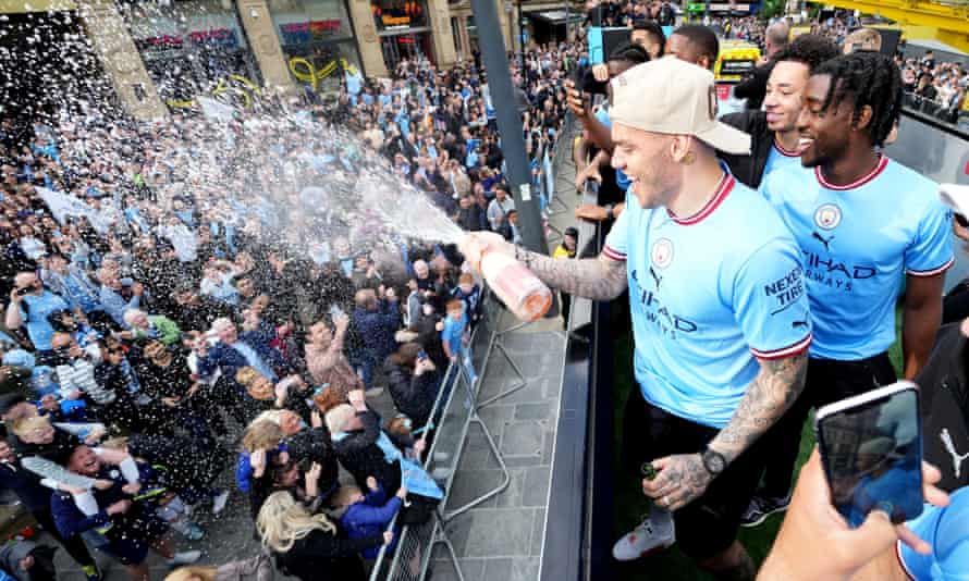 Ederson sprays champagne from the victory parade bus.
