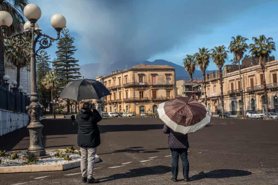 People in the town of Giarre use umbrellas as protection against volcanic ash.