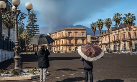 CItizen of Giarre cover their heads from volcanic ash from Mount Etna