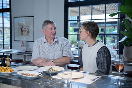 A man and woman facing each other, side by side at a restaurant table