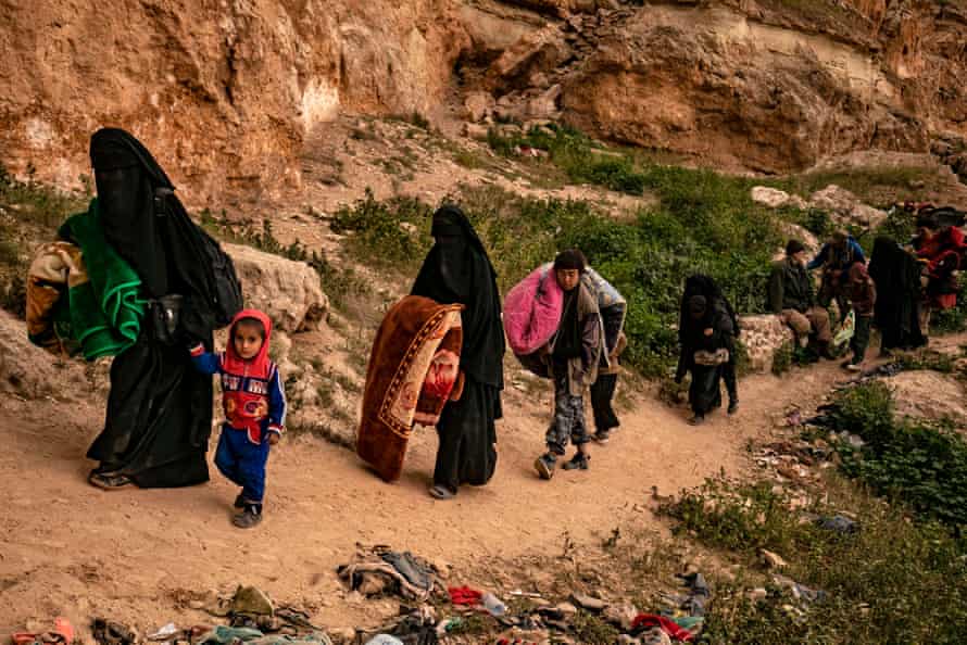 Women and children leave the village of Baghuz, in the eastern Syrian province of Deir Ezzor, 14 March