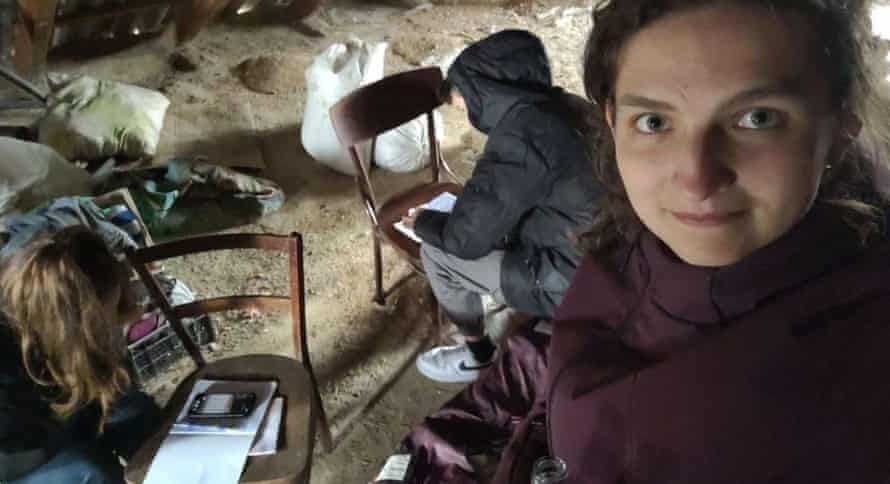 Женщина стоит возле камеры, пока студенты работают за ней