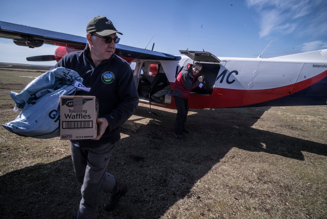 Ricky Evans carries a waffles box and bag past a small plane