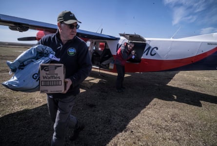 Ricky Evans carries a waffles box and bag past a small plane