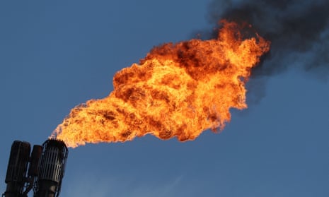 A pilot flame burns atop a Shell refinery.