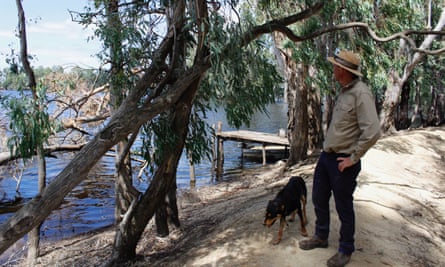 Riverina farmer Peter McDonald with his dog Syd stands on the levee bank at his farm near Caldwell, NSW, Australia, January 2023.