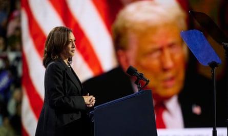 Kamala Harris speaking at a podium with an image of Trump behind