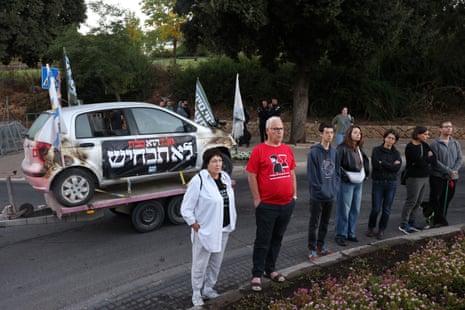 People stand next to a damaged car outside the Knesset.