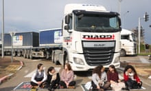 Israeli protesters sitting in front of a stationary lorry