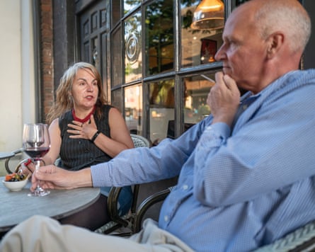 Becky and Andy sitting chatting at a small table outside the front of a restaurant
