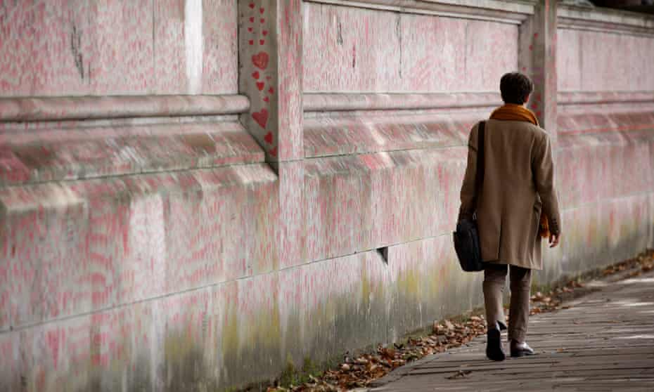 A woman walks beside the National Covid Memorial Wall in London, more than 800 Covid deaths have been reported in the past seven days.