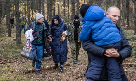 Alaa Massini (centre), a refugee from Syria, speaks with Klara, an activist from Grupa Granica, as Alaa's husband, Muhammad, carries one of their children in woods near Kleszczele, Poland