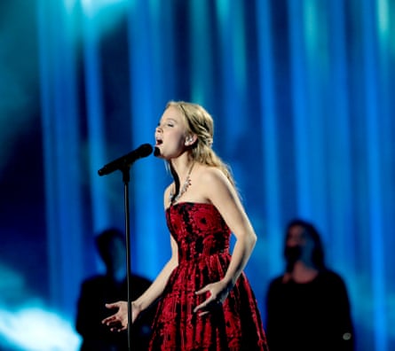 Zara Larsson wearing a red dress singing into a microphone