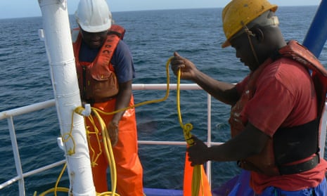 Crewmen attaching bird-scaring lines to an industrial trawler in Namibia.