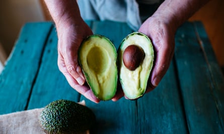 Hands holding two halves of an avocado