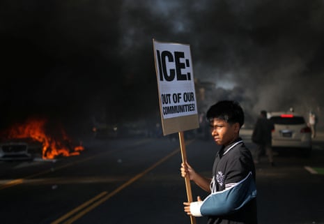 A demonstrator holds a placard during a protest against federal immigration sweeps in downtown LA, 8 June, 2025.