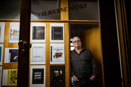 A man standing in a doorway with a sign that says ‘Melbourne Books’ above, and book covers displayed to the left