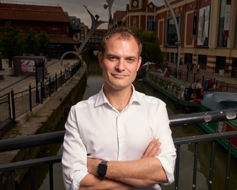 Hamish Falconer standing with arms folded on a bridge over a canal in Lincoln