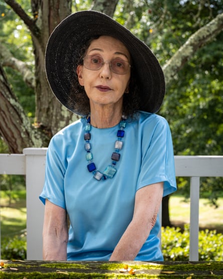 A woman wearing glasses and a sun hat poses outside
