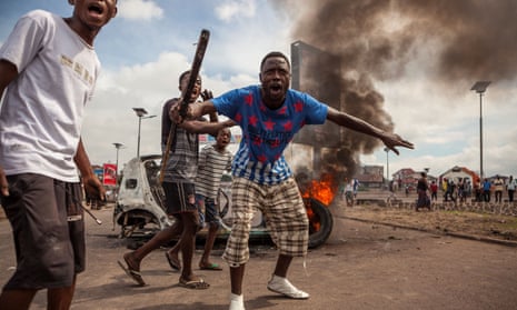 Demonstrators gather in front of a burning car during an opposition rally in Kinshasa.