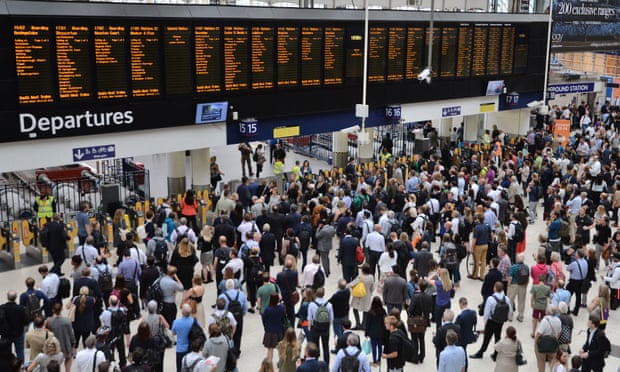 rail commuters look at the departures board at London Waterloo