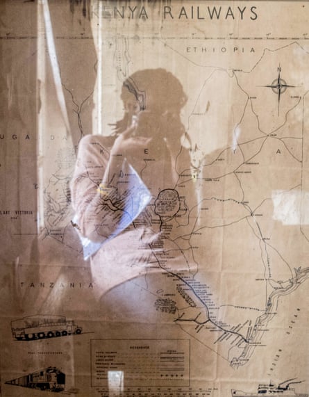 A woman reflected in a map she is photographing