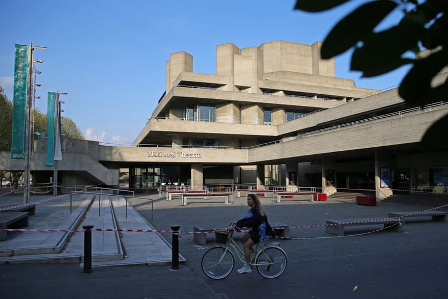 A cyclist rides past the National Theatre with its forecourt taped off to prevent use.