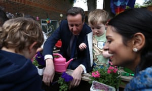 David Cameron plants flowers with children during a visit to a nursery in London