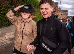 A couple holding hands smile as they get caught in a gust of wind.