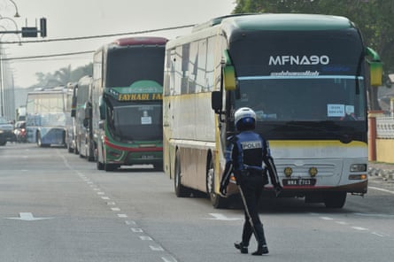 A policeman walks in front of buses carrying Myanmar nationals being repatriated from Malaysia.