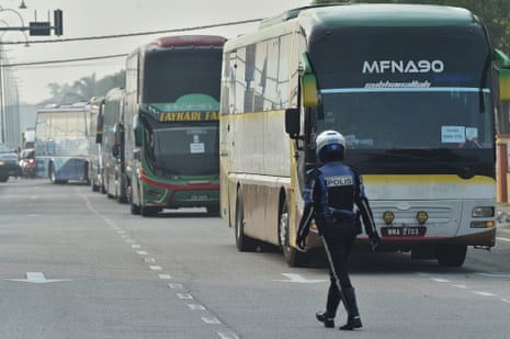 A policeman walks in front of buses in Kuala Lumpur carrying Myanmar nationals being repatriated from Malaysia despite concerns for their safety in the war-torn country.