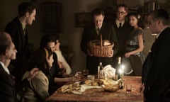 The Frank, van Pels, and Gies families celebrate Hanukkah in the upcoming limited series A SMALL LIGHT, from National Geographic and ABC Signature in partnership with Keshet Studios. From left: Liev Schreiber as Otto Frank, Ashley Brooke as Margot Frank, Rudi Goodman as Peter van Pels, Billie Boullet as Anne Frank, Amira Casar as Edith Frank, Caroline Catz as Mrs. van Pels, Noah Taylor as Dr. Pfeffer, Joe Cole as Jan Gies, Bel Powley as Miep Gies, and Andy Nyman as Mr. van Pels. (Photo credit: National Geographic for Disney/Dusan Martincek)