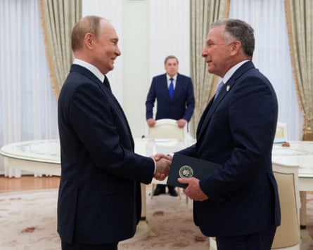 Vladimir Putin and Steve Witkoff shake hands.
