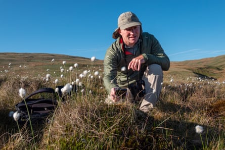 A man crouches among flowers and grass