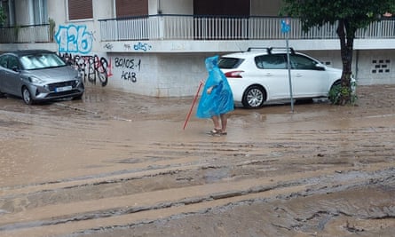 A person walking through rainwater in the Greek city of Volos