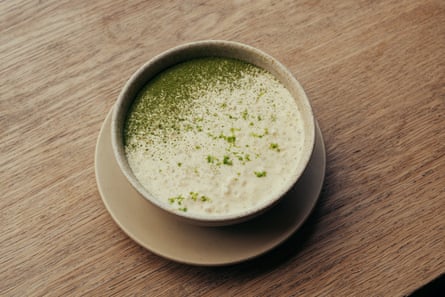 A speckled bowl holds creamy rice pudding dusted with green powder and lime zest, on a saucer