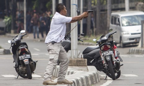 A plainclothes police officer aims his gun at attackers during a gun battle following explosions in Jakarta, Indonesia