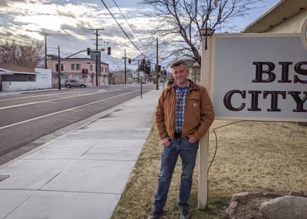 man stands next to sign with the letters “BIS” and “CITY” visible, on street