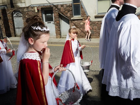 Eight-year-old girls dressed as Brides of Christ kiss petals representing the blood of Jesus, at a Eucharistic procession in Cork city