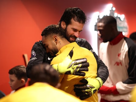 Alisson Becker of Liverpool and his fellow Brazil international Matheus Cunha of Wolves embrace in the tunnel prior to their match at Anfield