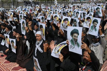 Mourners hold up pictures of Mojtaba and Ali Khamenei.