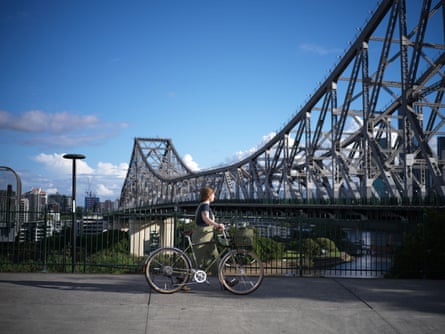 A woman wheels her bike towards bridge