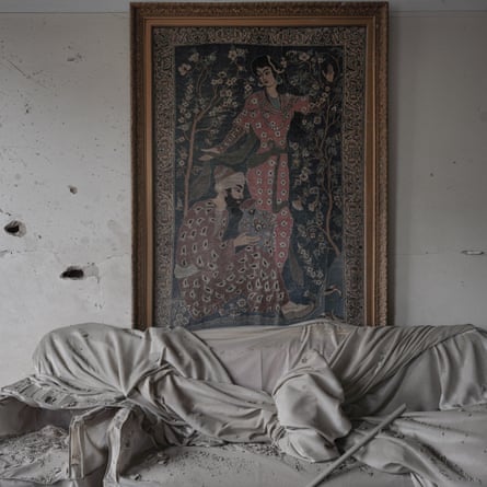 Damaged interior, tapestry on wall and dustsheet covering something in front of it