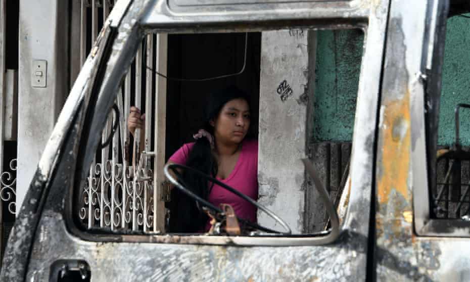 A woman looks at a bus burnt by gang members in Honduras. 