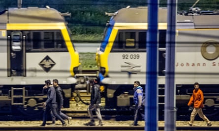 Migrants walk along railway tracks at the Eurotunnel terminal.