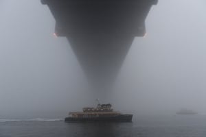 A ferry under the Sydney Harbour Bridge shrouded in fog.