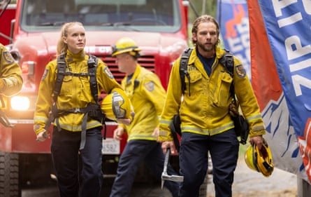 Three people in yellow fireproof jackets and yellow hardhats in front of a fire engine